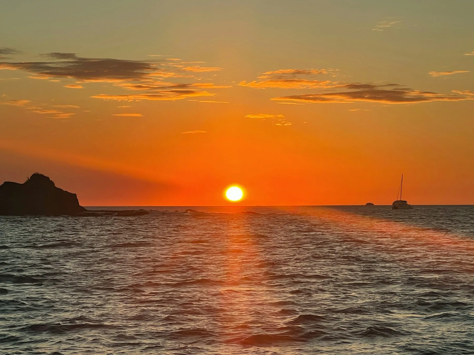 Catamaran au mouillage face au soleil couchant.